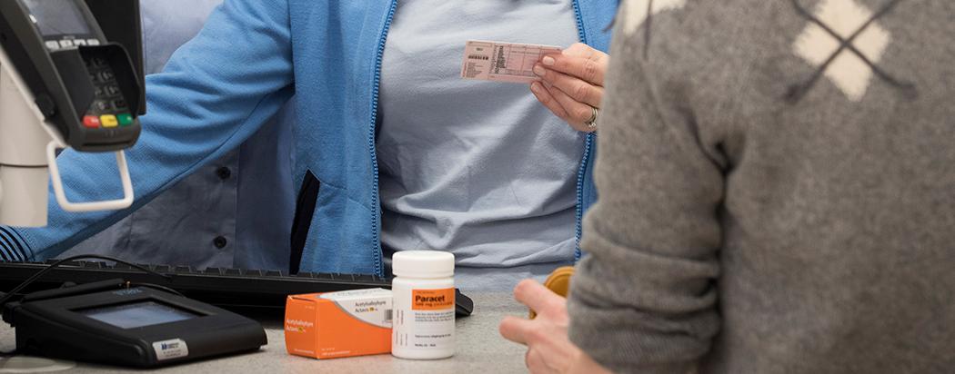 Person viser legitimasjon på apoteket. Foto.