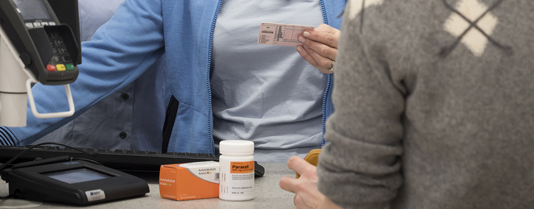 Person viser legitimasjon på apoteket. Foto.